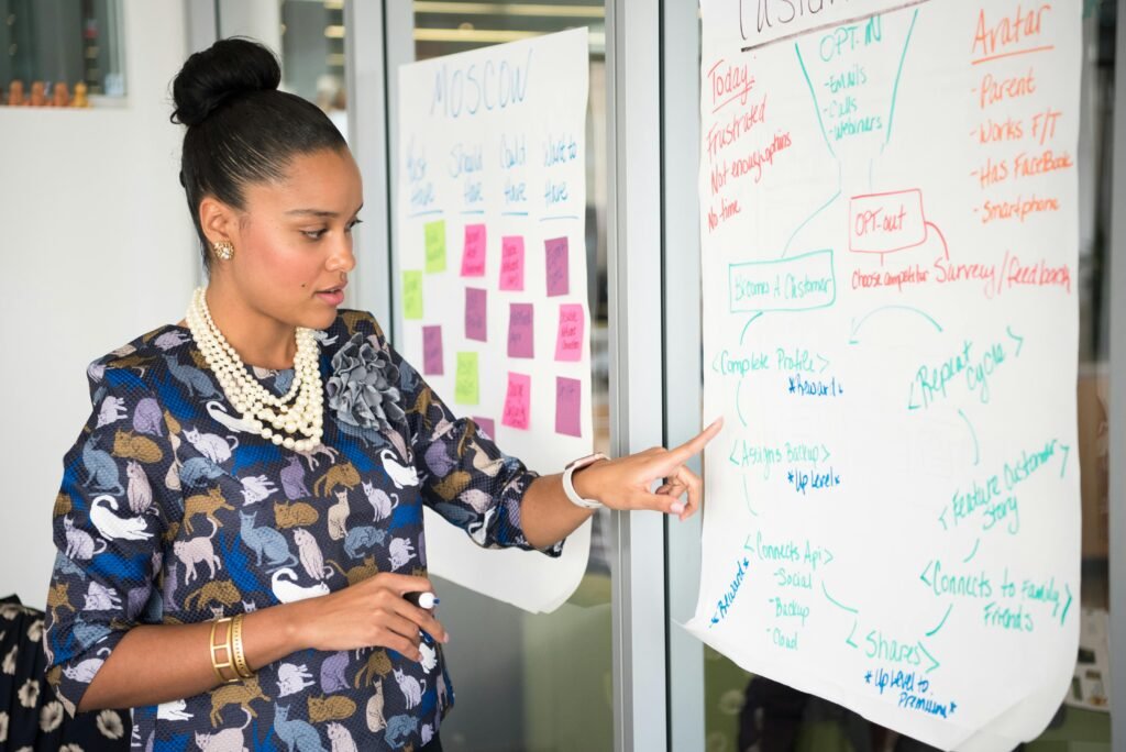 pexels-photo-1181623-1181623 Professional woman presenting business strategy on paper in office. Engaged in workplace discussion.