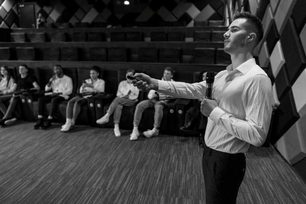 pexels-photo-7234415-7234415 Monochromatic image of a speaker presenting to a small audience in a stylish auditorium.